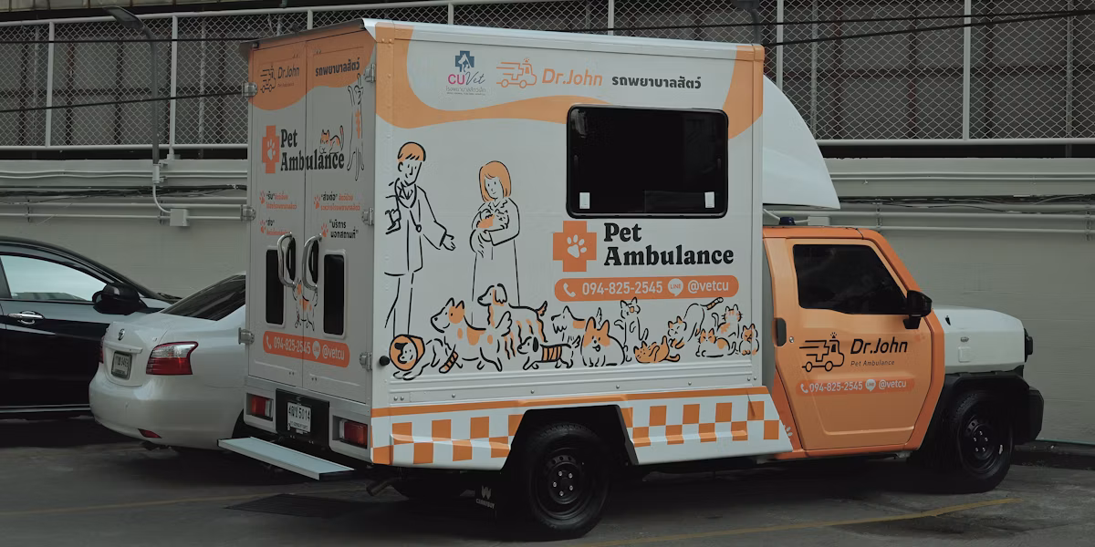 Ambulanță veterinară albă și portocalie cu ilustrații de animale